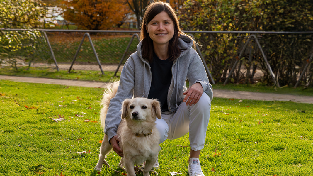 Tierärztin Lisa hockt auf einer Wiese neben einem Hund